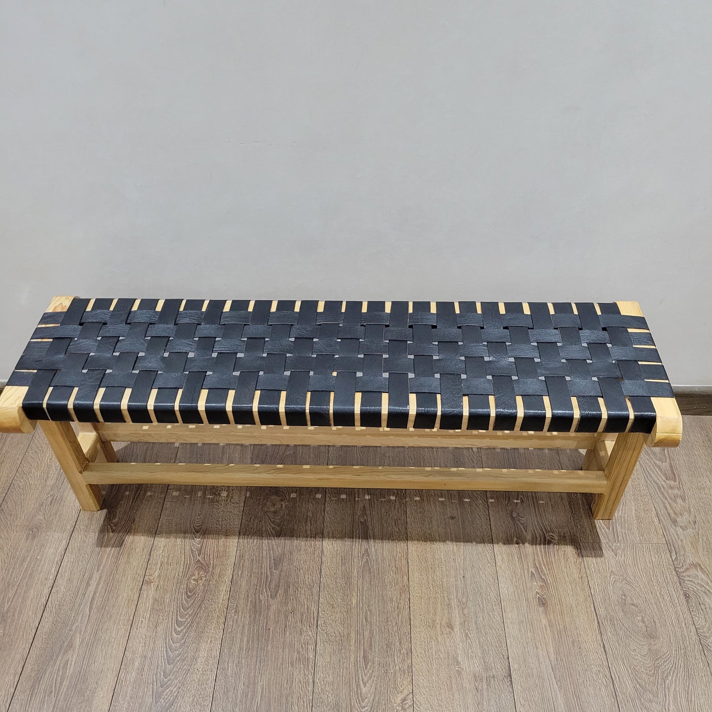 Woven Leather Bench — side view of artisan stitching
